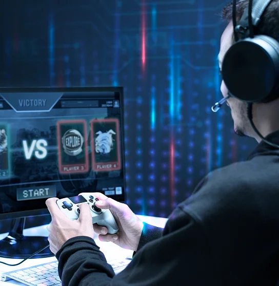 Une personne portant des écouteurs joue à un jeu vidéo sur un écran affichant un menu « VS » avec des personnages du jeu. L'ambiance est tamisée, avec un fond éclairé d'une lumière bleue